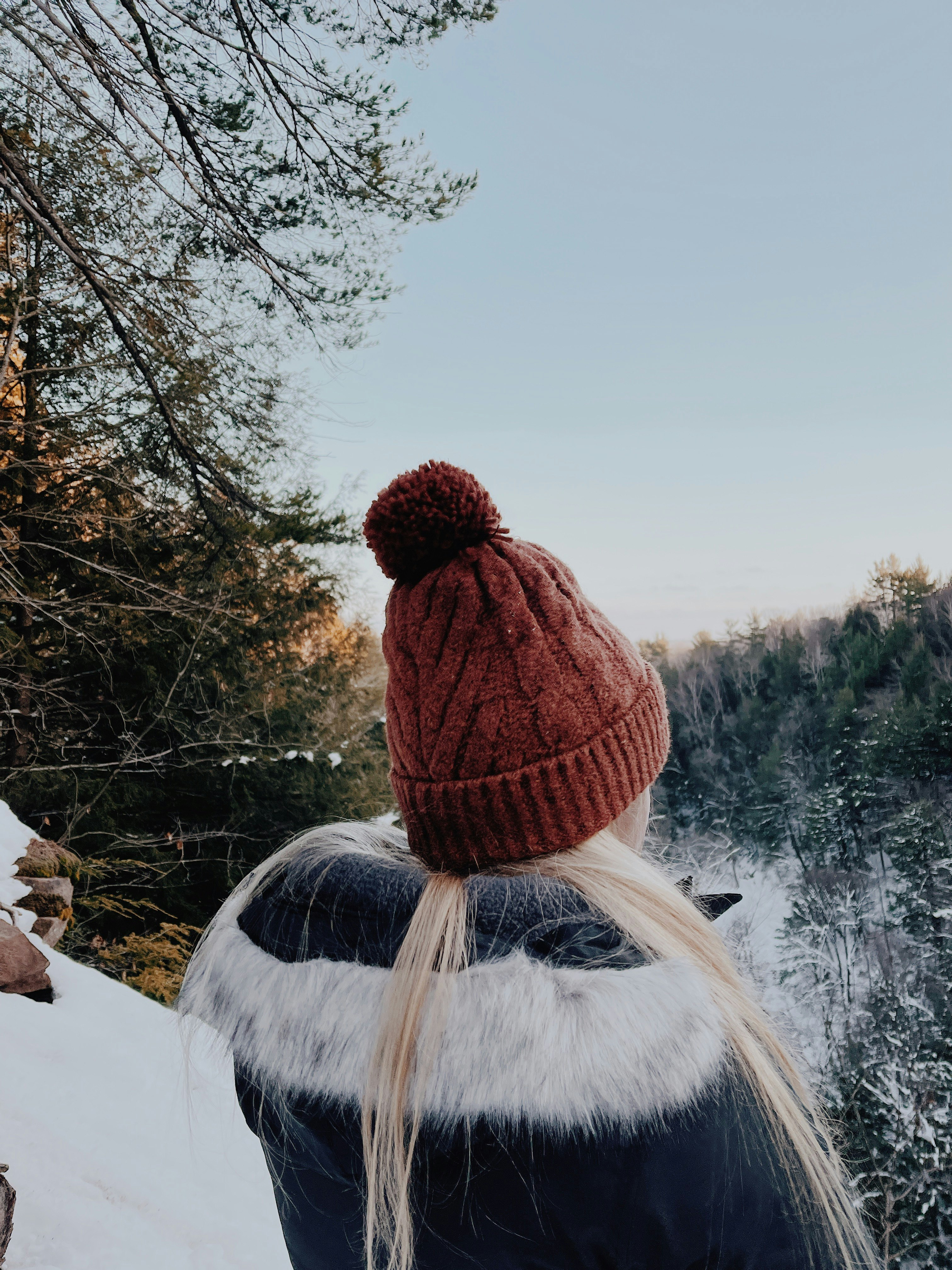 person in brown knit cap and white jacket standing on snow covered ground during daytime